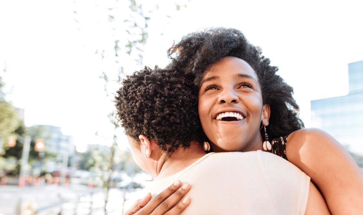 Image of two women embracing, both smiling and enjoying the moment together.