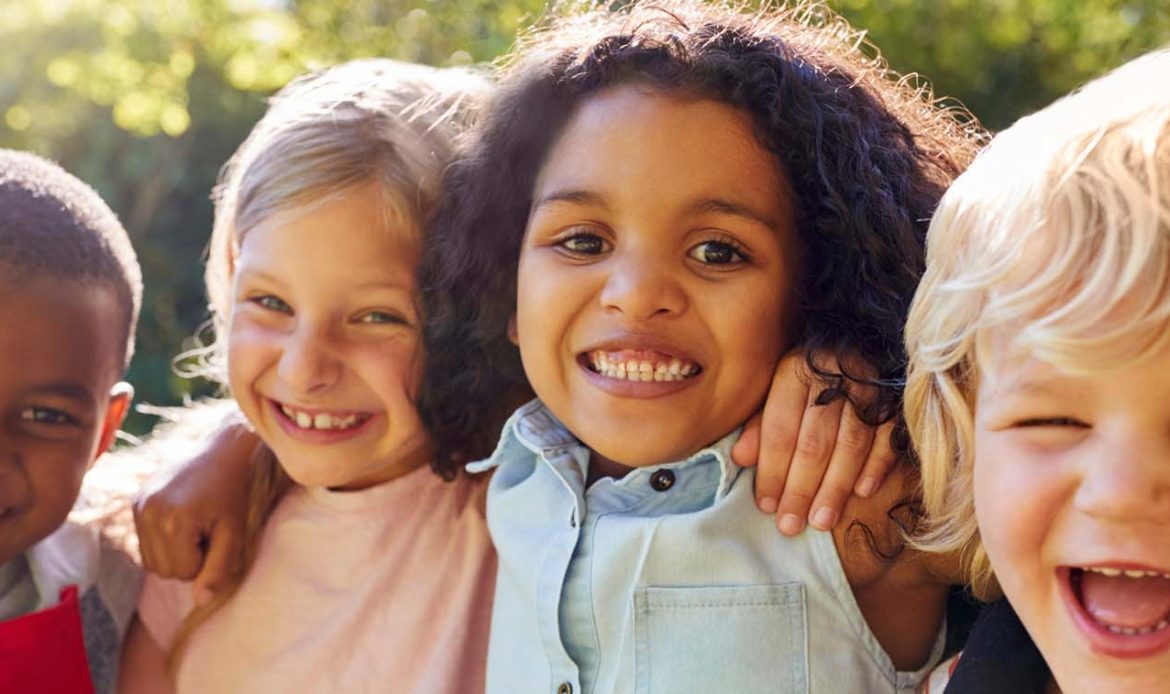 Group of happy children outdoors, symbolizing the positive impact of raising mentally strong kids.