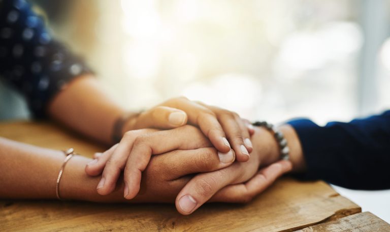 Two people holding hands learning how to deal with grief