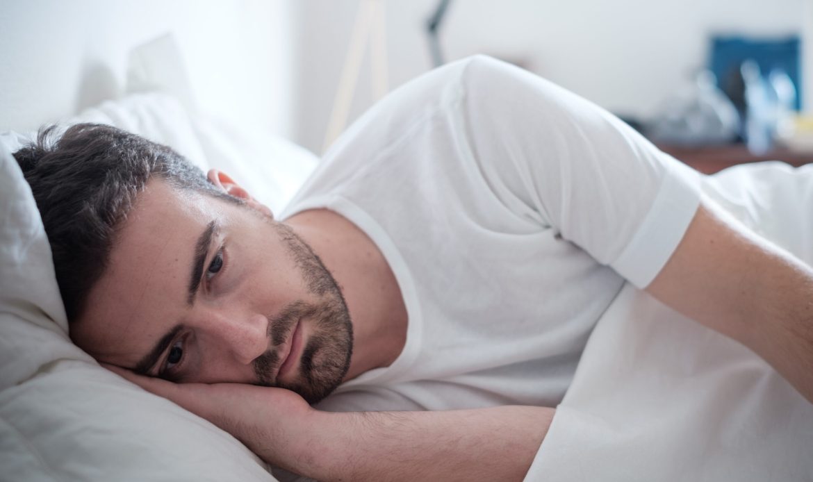 Depressed man lying in his bed and feeling bad