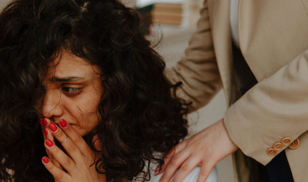 Distressed woman with hands covering her mouth, being comforted by another person, illustrating the emotional impact of trauma or stress-related disorder.