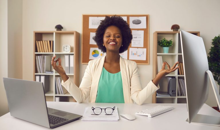 Young woman sitting at office desk and meditating focusing only on positive emotions