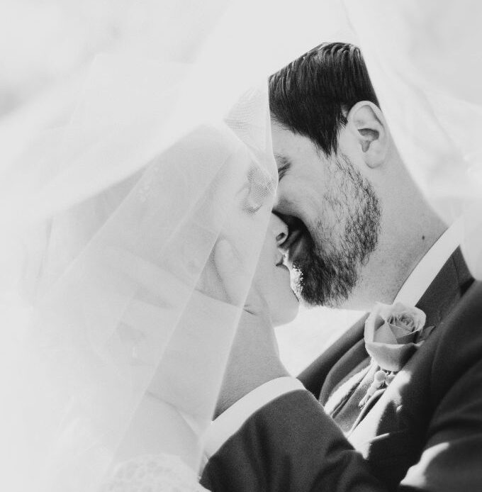 A bride and groom sharing an intimate moment under a veil, symbolizing cherished memories and the profound loss of a husband.