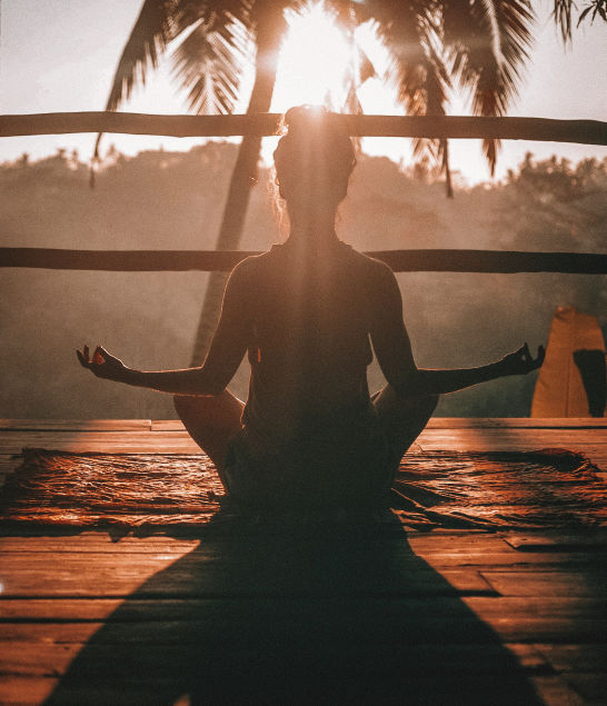 A person meditating at sunrise, reflecting a moment of calm and coping when feeling overwhelmed.