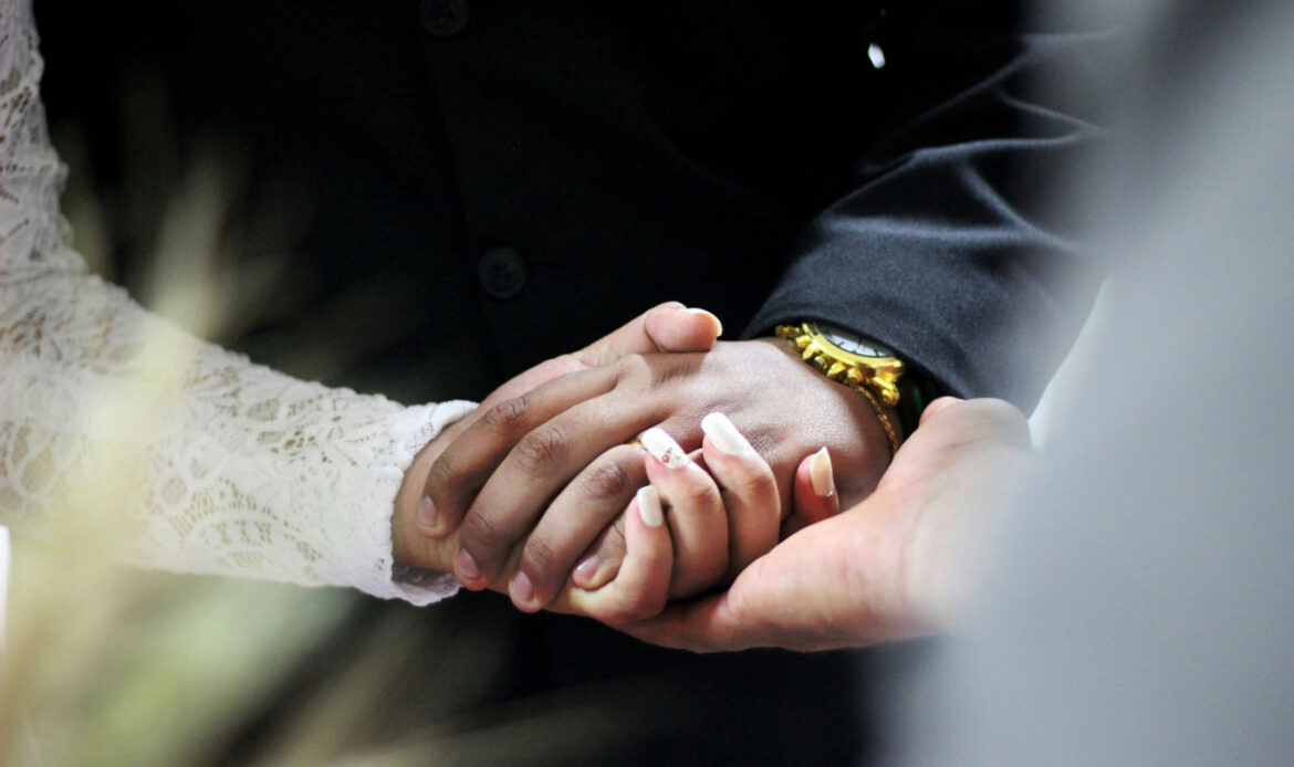 A woman holding her husband's hand, reflecting on love and loss after his passing.