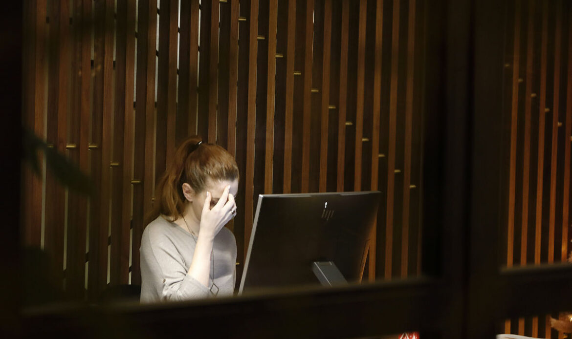 Employee experiencing social anxiety at work, stressed in front of a computer.