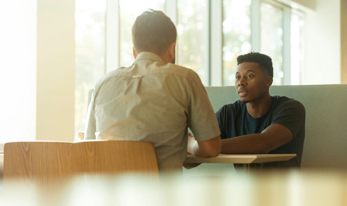 Two people having a discussion in a counseling setting, representing seeking professional help on how to break a trauma bond.