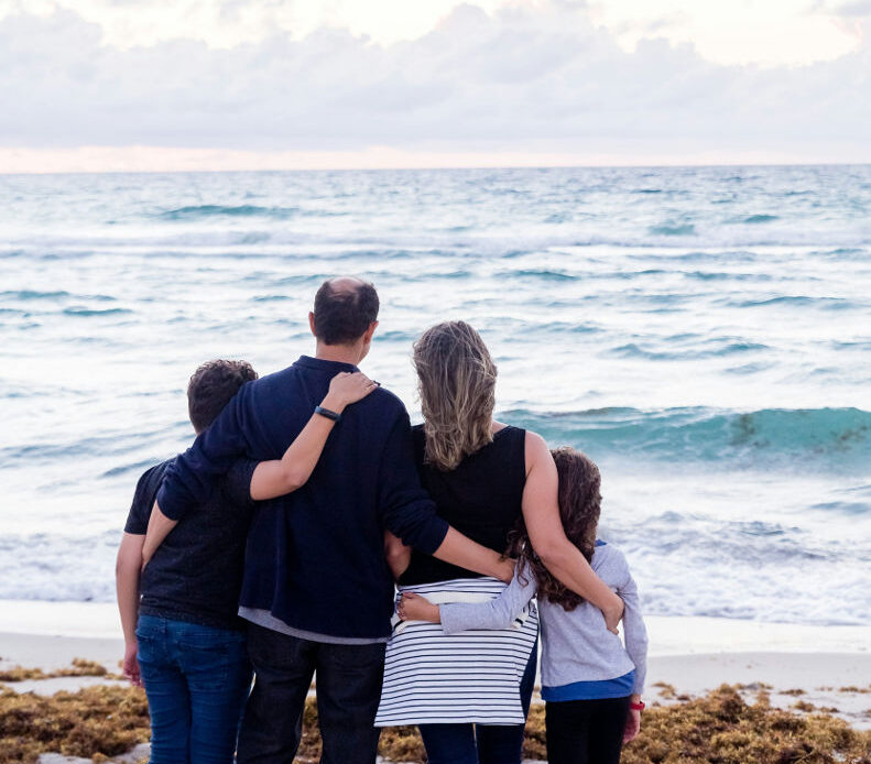 Family members embracing each other while looking at the ocean, symbolizing building a support system.