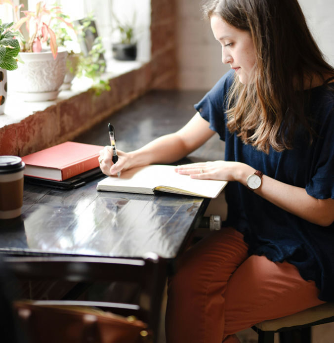 Creating Personal Rituals for Mourning shown through a woman journaling at a desk.