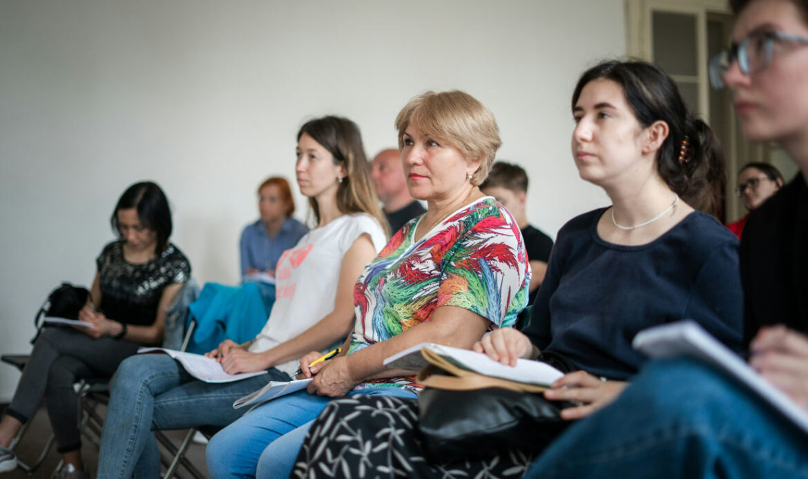 Group of individuals attentively listening in a seminar, symbolizing the supportive environment of a grief retreat—discover if a grief retreat is for you."