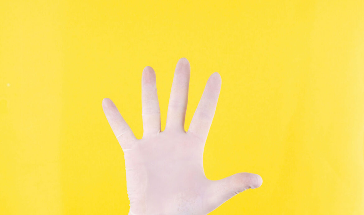 A hand wearing a white glove is raised against a bright yellow background, symbolizing taking five minutes for yourself to pause and reset.