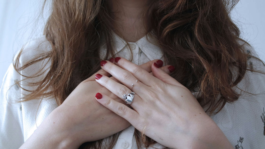 A woman gently places her hands over her chest, symbolizing self-soothing and the practice of calming emotional triggers.