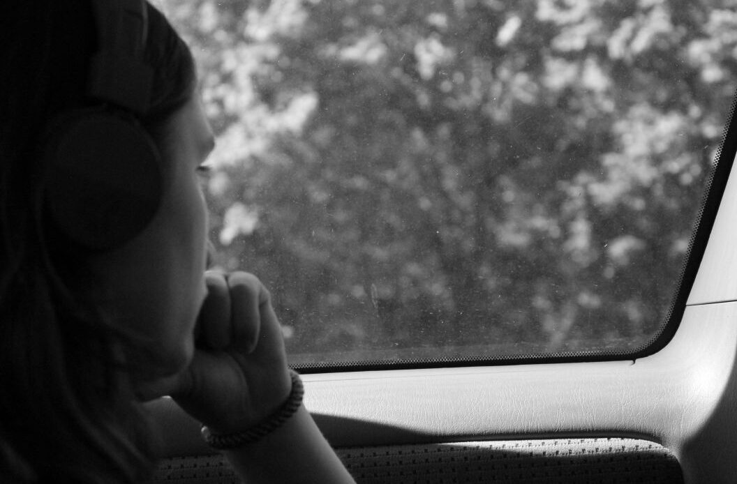 A woman sits quietly by a car window, deep in thought, representing how loss can reshape identity and daily life, and the need for thoughtful words when comforting a woman who has lost her husband.