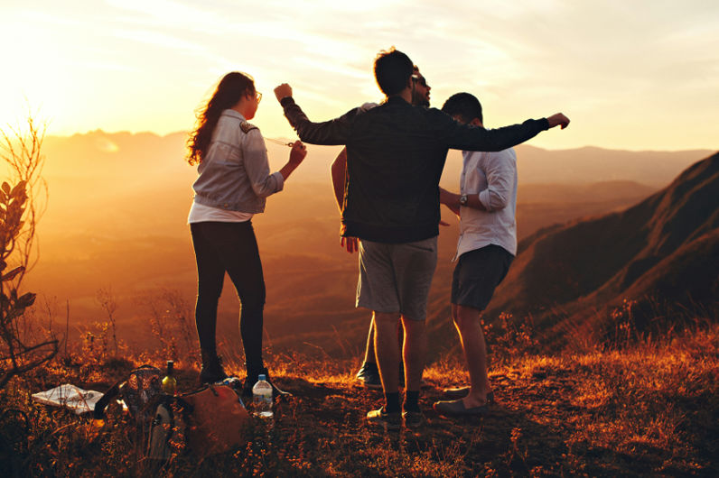 A group of friends stands together on a hill at sunset, symbolizing the strength and comfort of having a reliable support system.