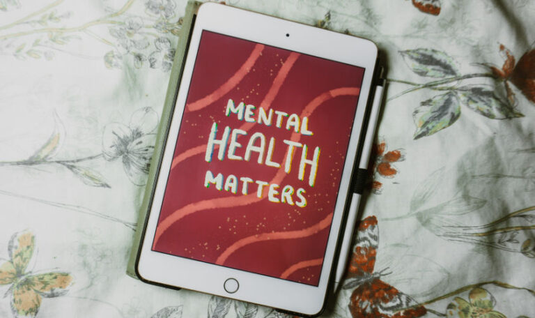 A tablet displays the words "Mental Health Matters" on a red background, representing the importance of setting and achieving mental health goals.