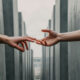 A woman’s hand reaches out towards another hand, symbolizing longing, grief, and the emotional connection to a husband she has lost.