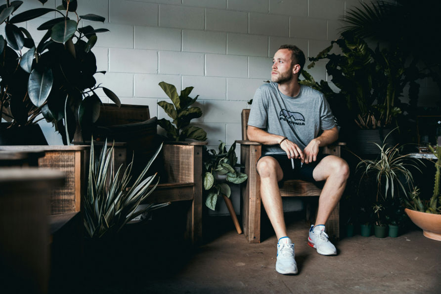 Man sitting in a wooden chair surrounded by plants, reflecting on overcoming the obstacles of starting over.