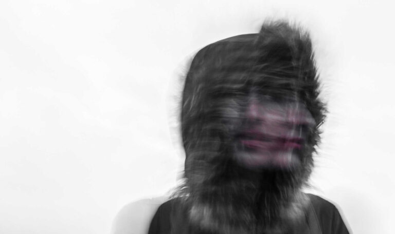 A blurred image of a person in a fur-lined hood, visually representing the disorienting and overwhelming feeling of spiraling mentally.