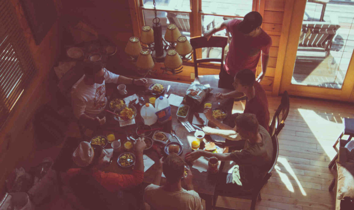A group of people gathered around a dining table sharing a meal, capturing the warmth and connection of meeting new people and building community.