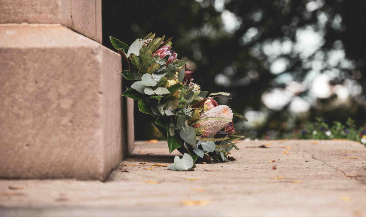 Pink and green flower bouquet against a brown concrete wall