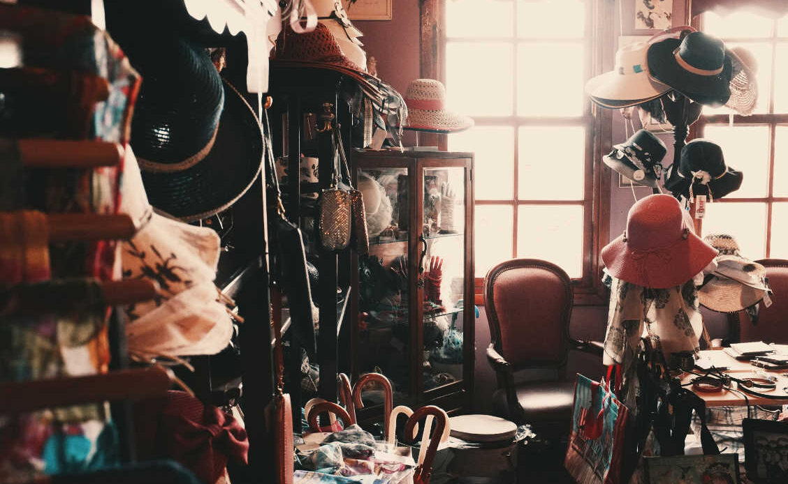 A vintage room filled with various hats, chairs, and accessories, symbolizing the process of exploring options and finding direction in life.