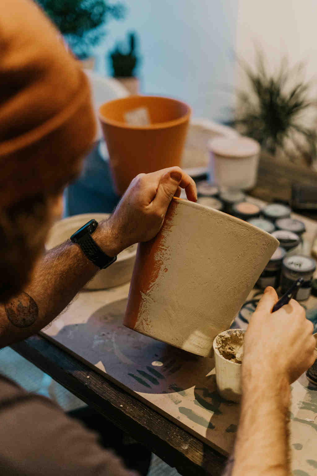A person painting a clay pot by hand at a workspace, representing the process of experimenting with creative activities while figuring out what to do with their life.