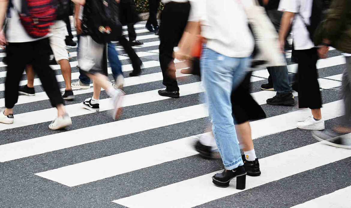 A crowd of people walking across a crosswalk, symbolizing the search for individuality and self-discovery amid the movement of everyday life.