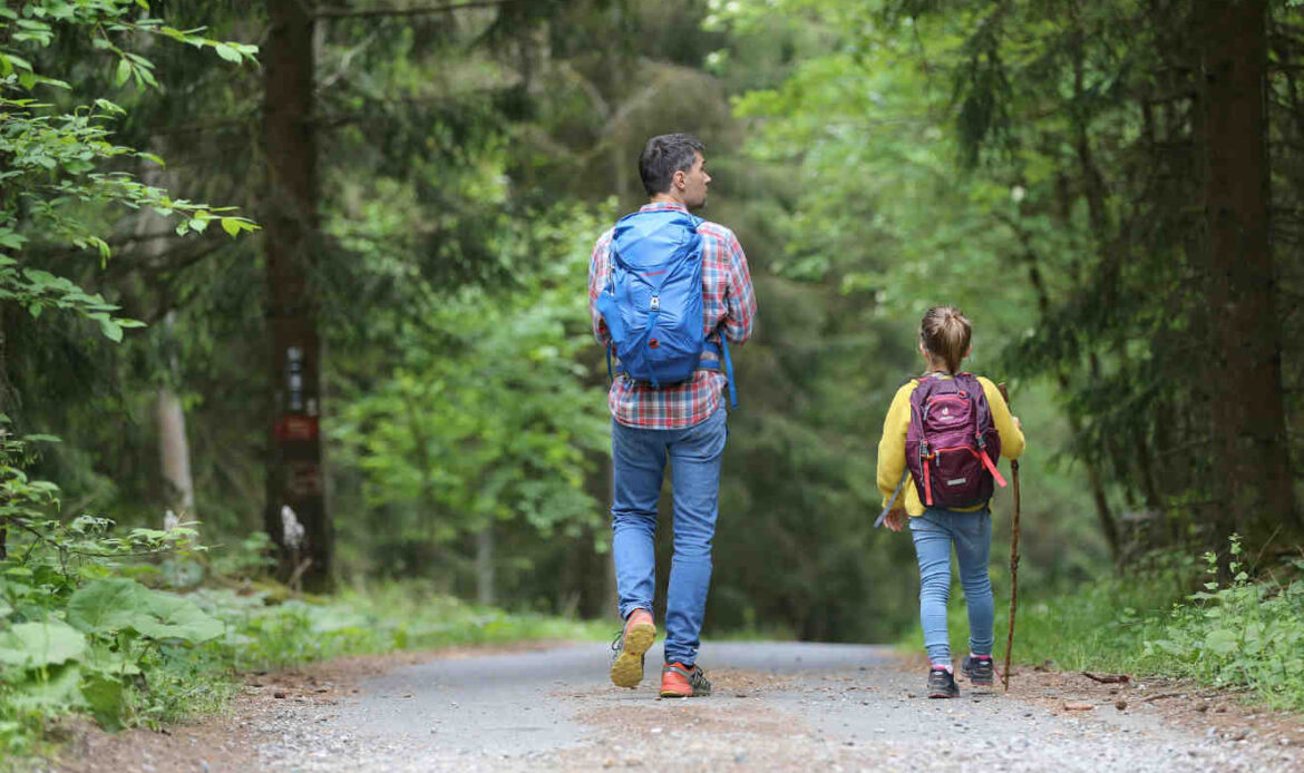 Man in blue jacket and jeans walking on a dirt road