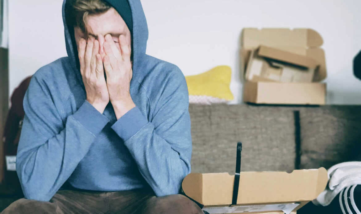Man sitting on a couch with his head in his hands, symbolizing the struggle of overcoming adversity.