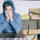 Man sitting on a couch with his head in his hands, symbolizing the struggle of overcoming adversity.