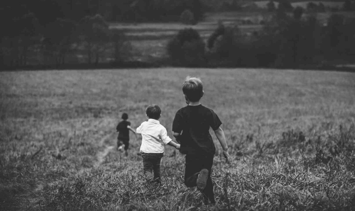 Three children running through a grassy field, symbolizing distant or blurry memories tied to early childhood experiences.