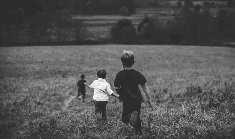 Three children running through a grassy field, symbolizing distant or blurry memories tied to early childhood experiences.