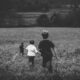 Three children running through a grassy field, symbolizing distant or blurry memories tied to early childhood experiences.