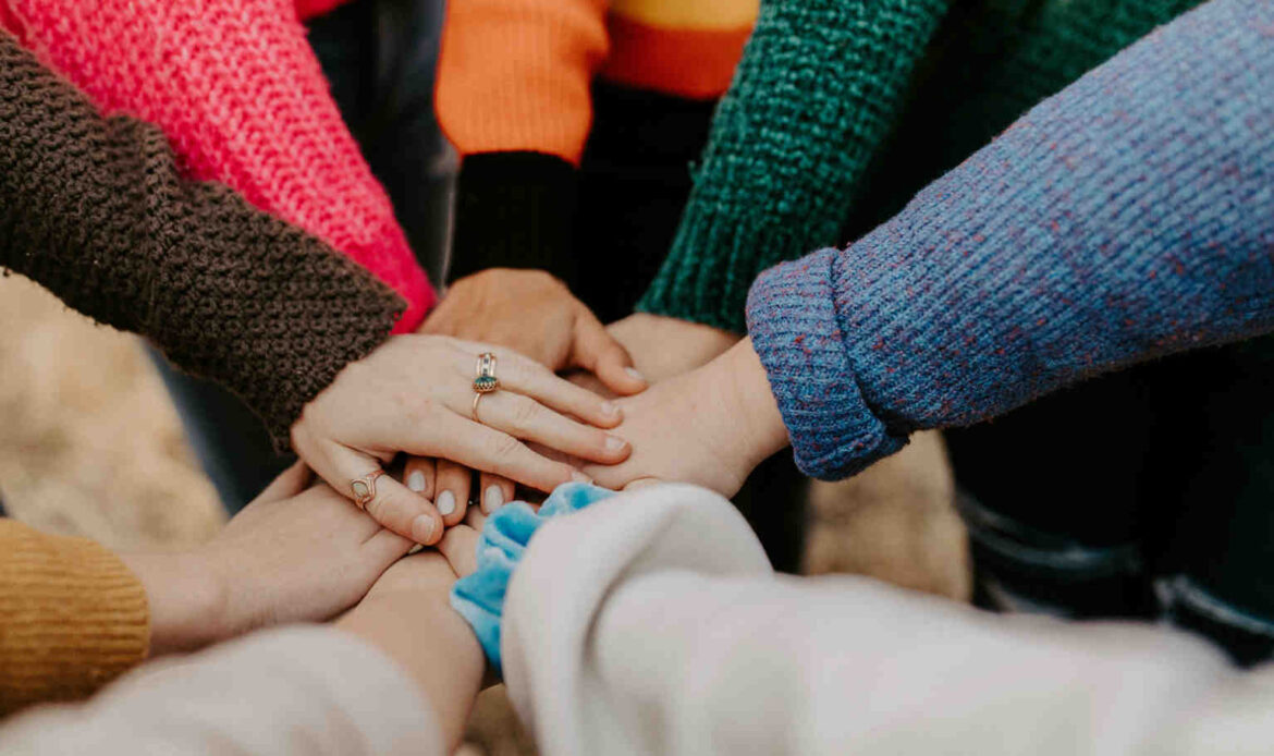 Adult in red sweater holding another woman’s hand