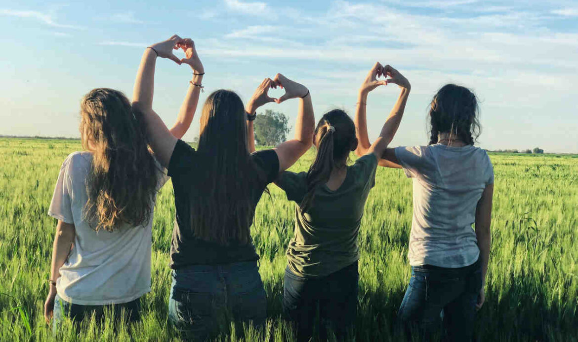 Women forming heart gestures outdoors