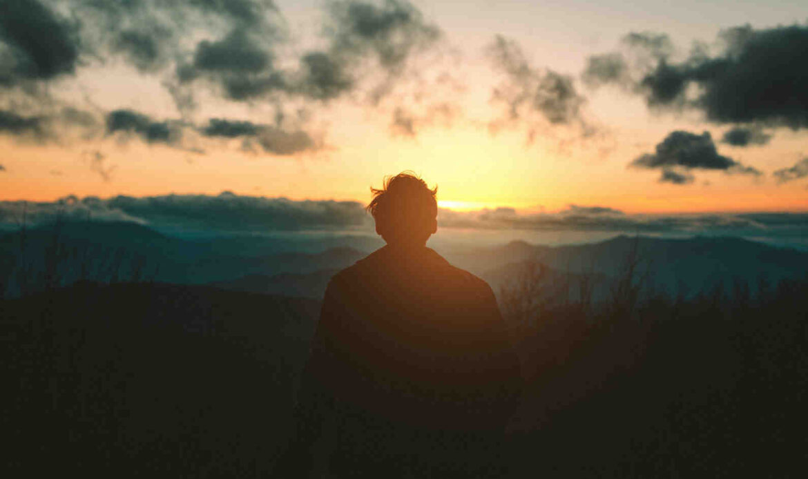 Silhouette of man on mountain at sunset