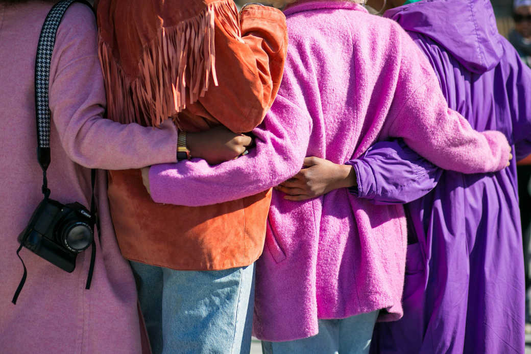 Four people linking arms outdoors