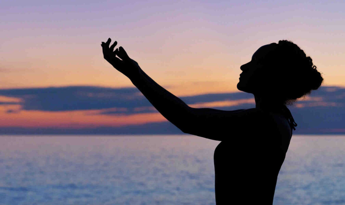Silhouette of woman raising hand