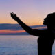 Silhouette of woman raising hand