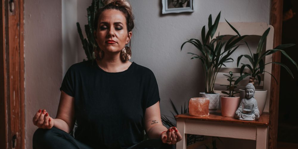 A person sits in a peaceful meditation pose surrounded by plants, symbolizing the importance of understanding oneself and embracing life with authenticity.