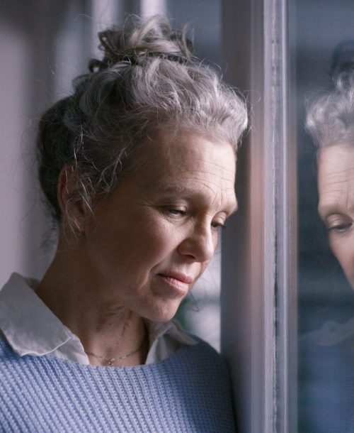 Grieving woman looking thoughtfully out a window.