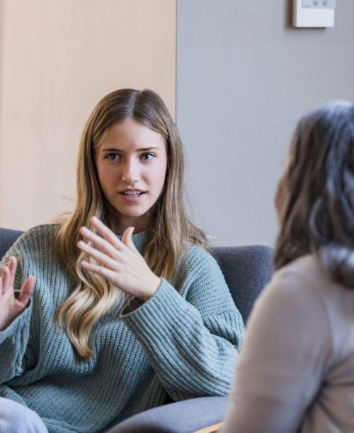 A woman engaged in a conversation with another person, representing the application of the Mentally STRONG Method for professionals.