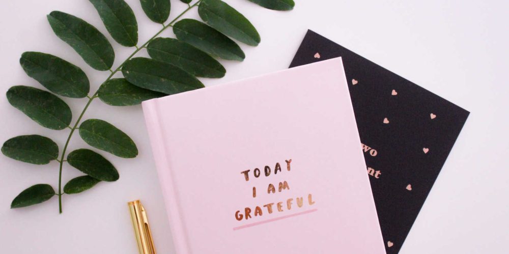 Attitude of gratitude journal with a pen and leaves, promoting daily mindfulness and thankfulness practice.